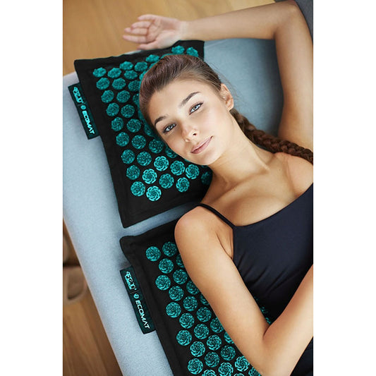 Mergina masažuoja nugarą ir kaklą ant ECO akupresūros masažinio kilimėlio su pagalvėle