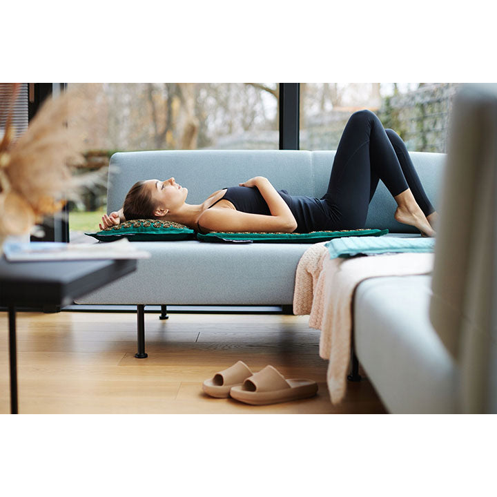 Mergina masažuoja nugarą ir sprandą ant masažinio kilimėlio su adatomis